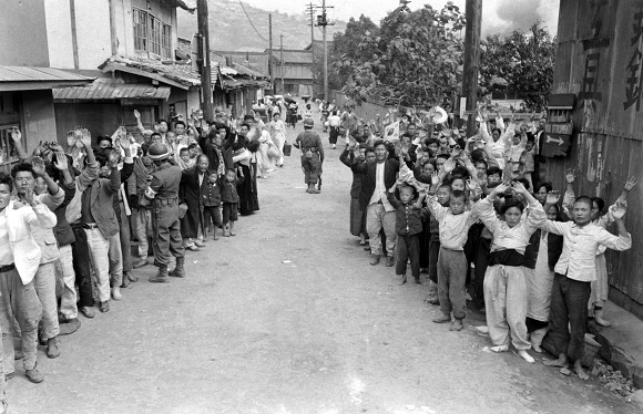여순사건 당시 군인들이 협력자를 색출하는 동안 머리 위로 손을 들고 있는 주민과 어린이들.